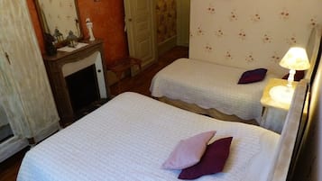 A room with two beds, a mirror, a small table, and a lamp.
