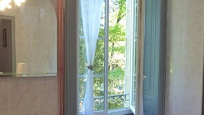 A bathroom with a pedestal sink, a bathtub, and a window with curtains. - Château de Montsablé (Lezoux)