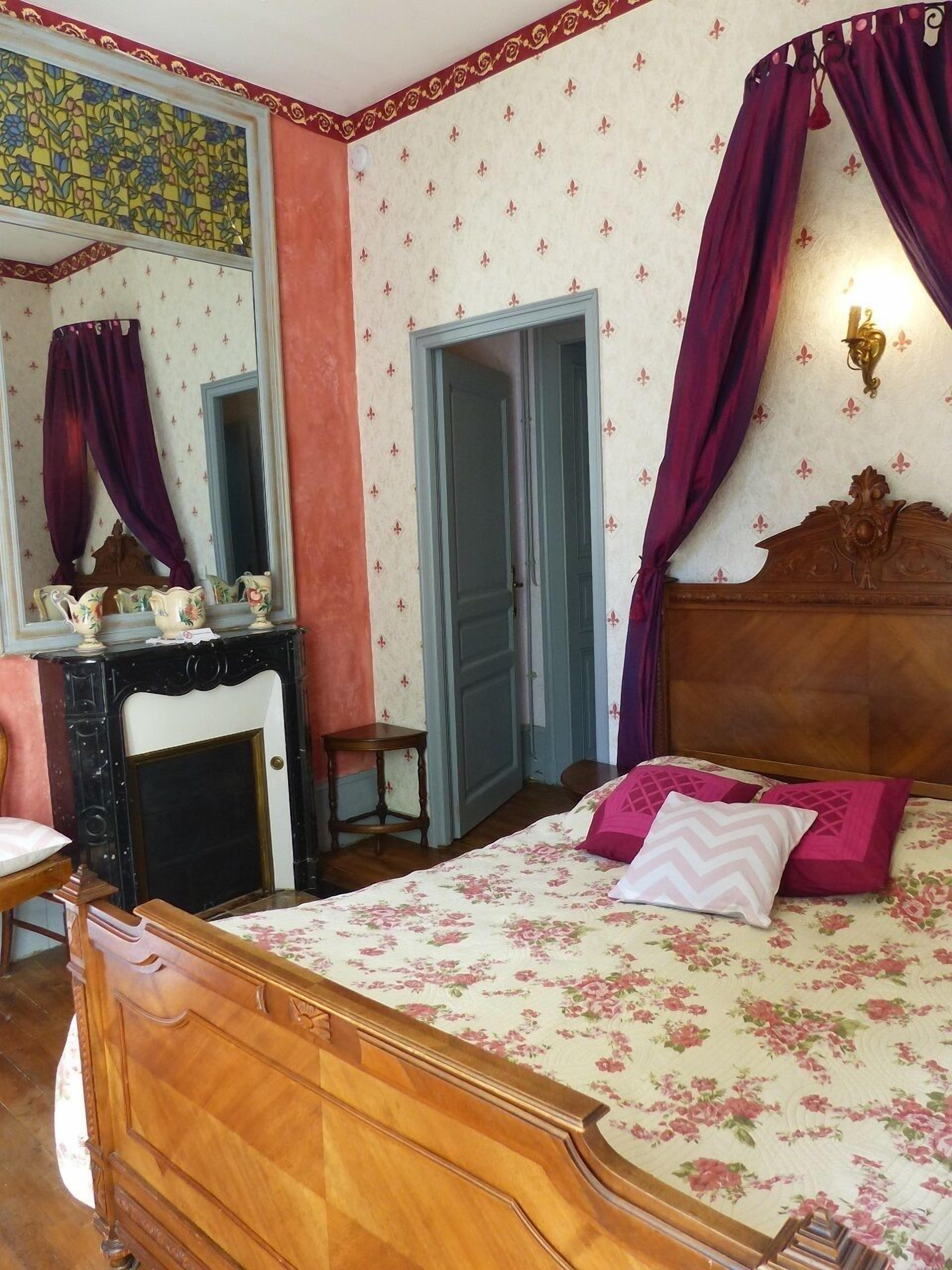 A bedroom with a wooden bed, a dresser, a mirror, and a door.