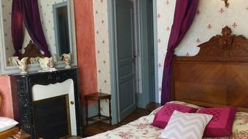 A bedroom with a wooden bed, a dresser, a mirror, and a door.