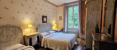 A bedroom with two beds, a dresser, a mirror, and a window with curtains.