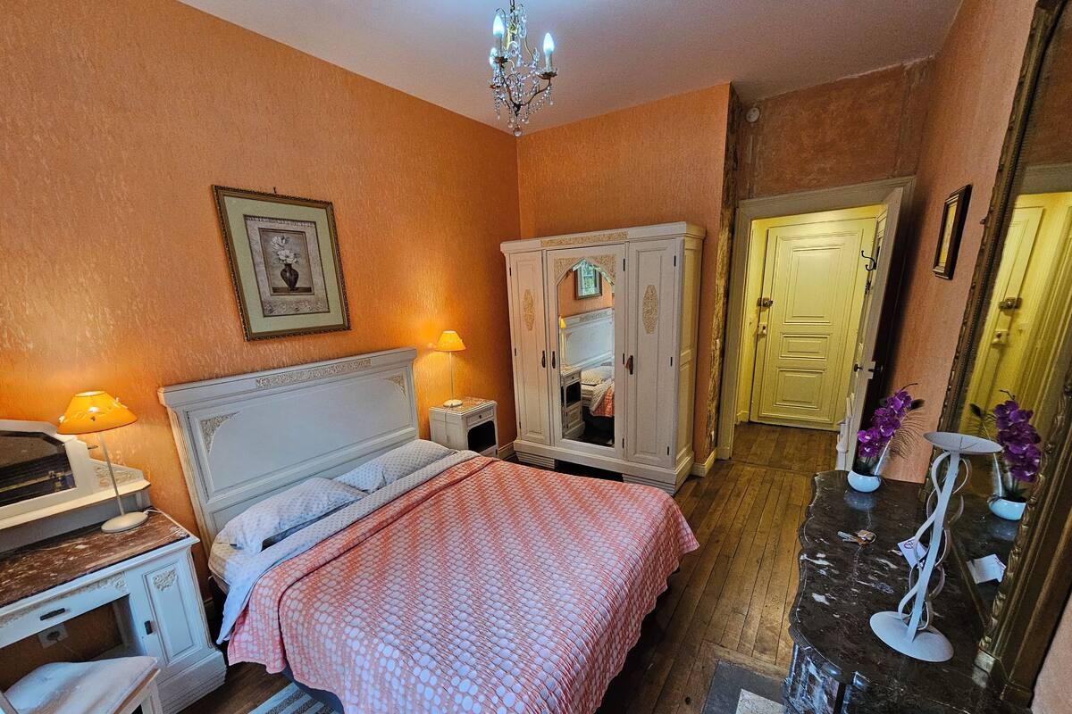Un dormitorio con cama, mesita de noche, lámpara, armario y espejo.