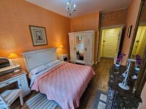 Une chambre à coucher comprenant un lit, une table de chevet, une lampe, une armoire et un miroir.