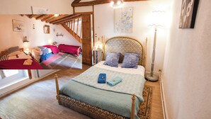 A bedroom with a large bed, wooden beams, a window, and a staircase. - Château de Montsablé (Lezoux)