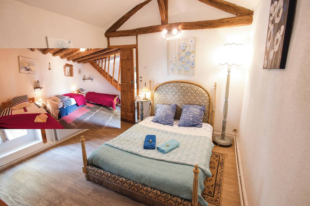 Un dormitorio con una cama grande, vigas de madera, una ventana y una escalera.