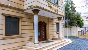 A building with a classical architectural style, featuring a prominent entrance with a wooden door and two columns. - Atropat Hotel Baku (Baku)