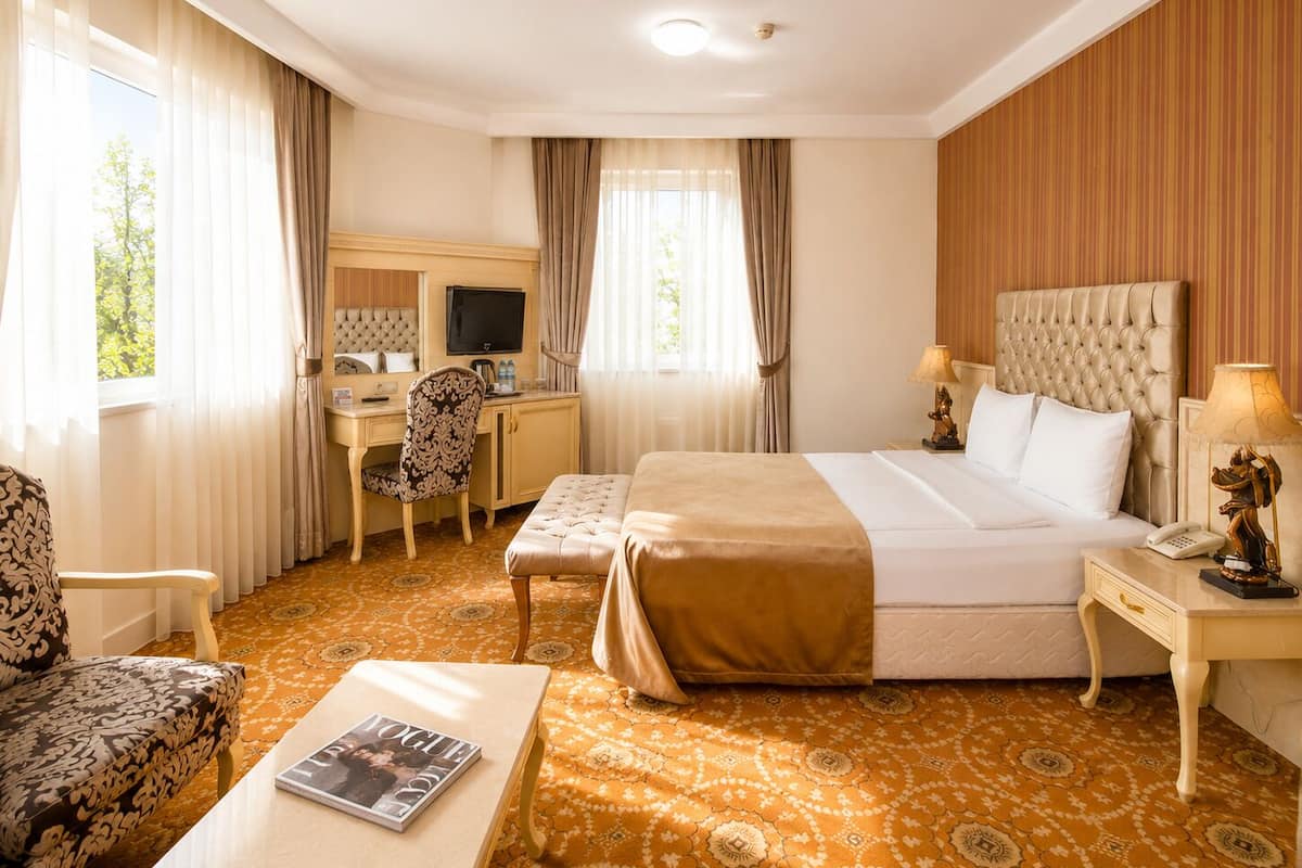 A hotel room with a bed, desk, chair, and a magazine on a table.