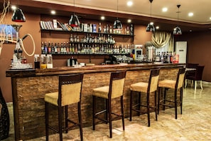 A bar area with a stone wall, wooden bar counter, and four bar stools. There are shelves with bottles and a hookah on the left. - Atropat Hotel Baku (Baku)