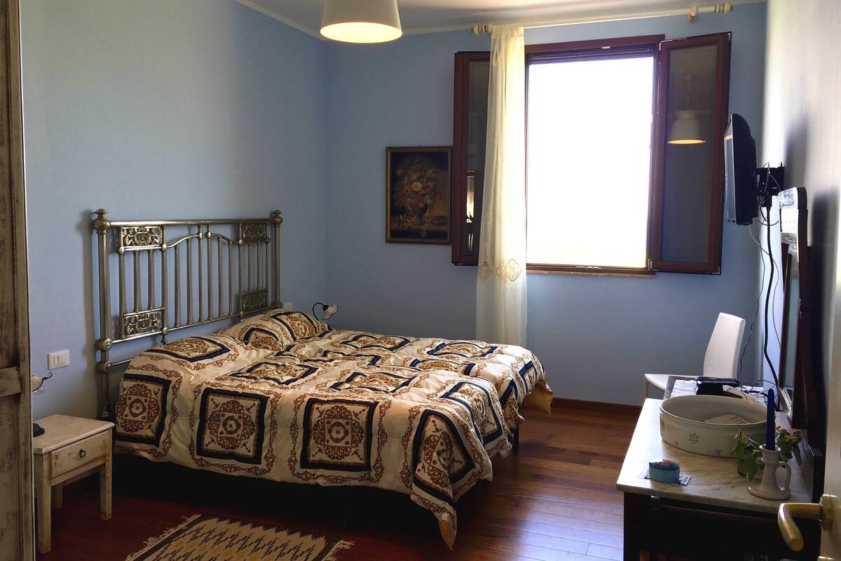 Une chambre à coucher comprenant un lit, un bureau, une chaise, une fenêtre et un téléviseur fixé au mur.