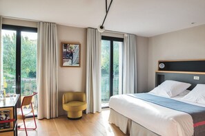 A hotel room with a bed, a chair, a desk with a computer, and a large window with curtains. - Hotel Brummell (Barcelona)