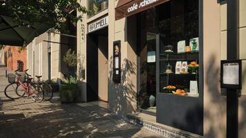 Una cafetería con toldo marrón y una pizarra con la carta.