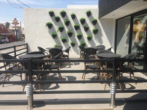 An outdoor seating area with tables and chairs, a wall with vertical planters, and a metal railing.