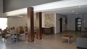 Un vestíbulo moderno con mostrador de recepción, zona de estar y máquina de café.