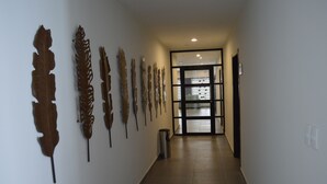Un pasillo con una serie de hojas decorativas montadas en la pared y un cubo de basura.