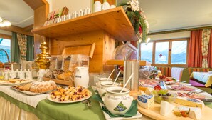 A buffet table with various food items, including pastries, cheese, and a large jug labeled 'Heidelbeer - Buehl'. - Seiterhof (Schladming)