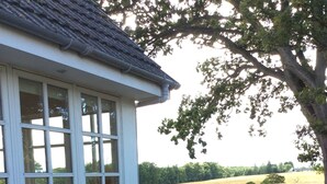 A stone building with large windows, a patio with a wooden table and benches, and a view of a field. - Westacre Lodge Self Catering Chalet (Crieff)