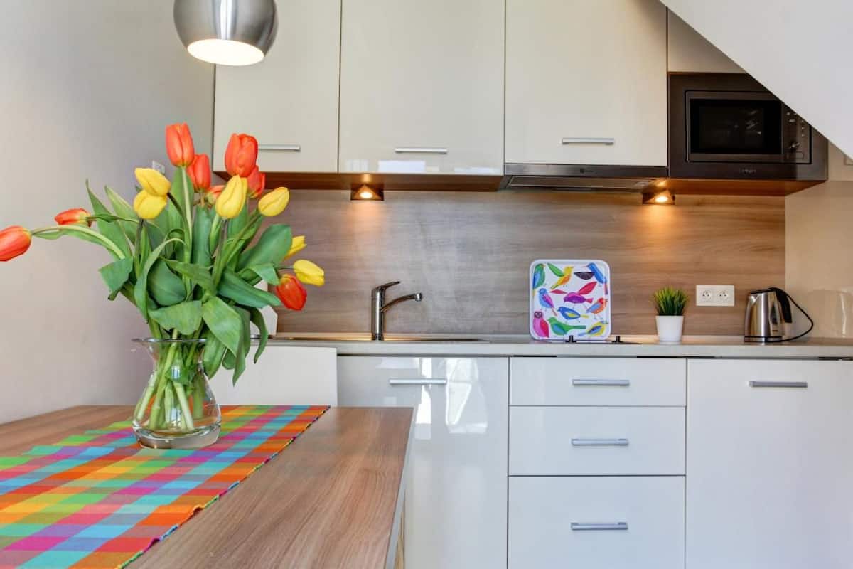 A modern kitchen with white cabinets, a stainless steel sink, and a colorful table runner.