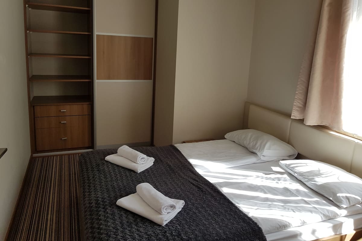 A hotel room with a bed, a wardrobe, and a window with curtains.