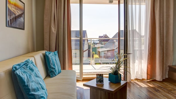 Un salon moderne avec un canapé, une table basse et une grande fenêtre avec des rideaux.