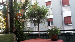 A balcony with a table covered by a red tablecloth, surrounded by potted plants and a small tree. - Easy Dream Rooms (Verona)