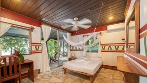 Un dormitorio con cama, escritorio, silla, ventilador de techo y ventana con cortinas.