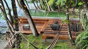 Una hamaca, terraza de madera y zona de estar con vista al agua.