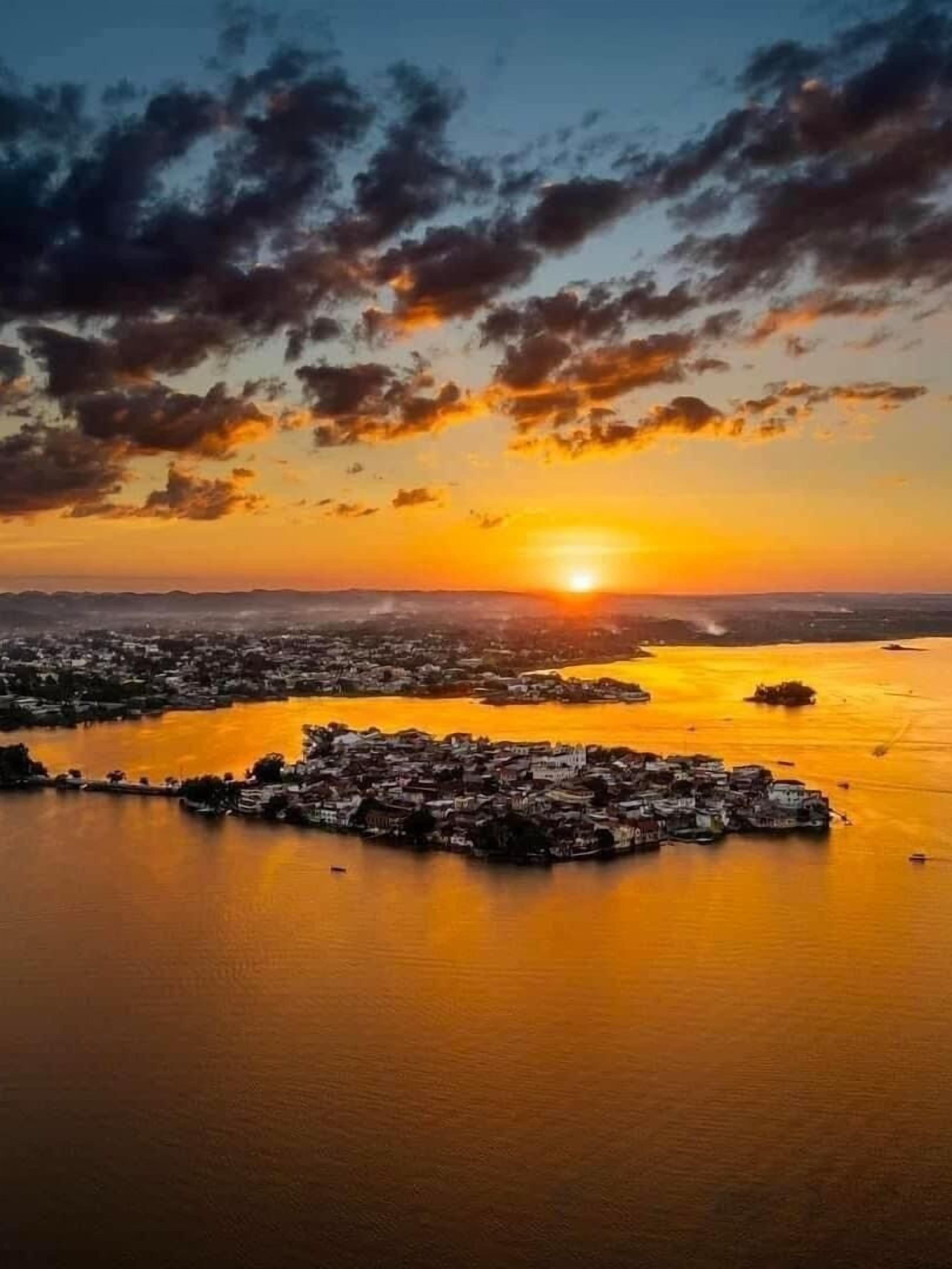 Vista aérea de un pueblo costero con un río y un atardecer.