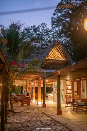A tropical resort with a thatched-roof structure, outdoor seating, and a bar area. - Hotel Gringo Perdido (San Jose Peten)