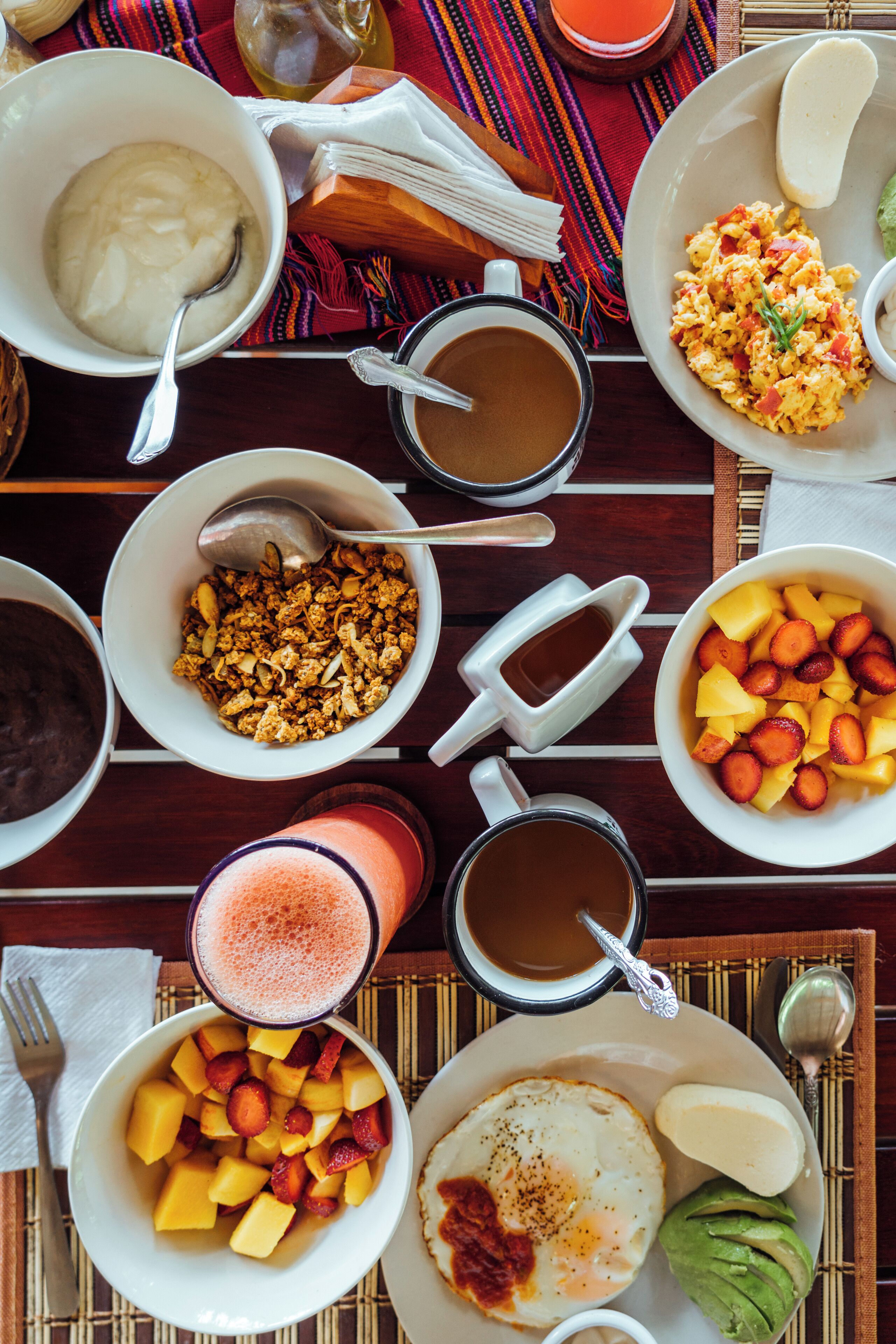 A breakfast table with various dishes including eggs, fruits, and beverages.