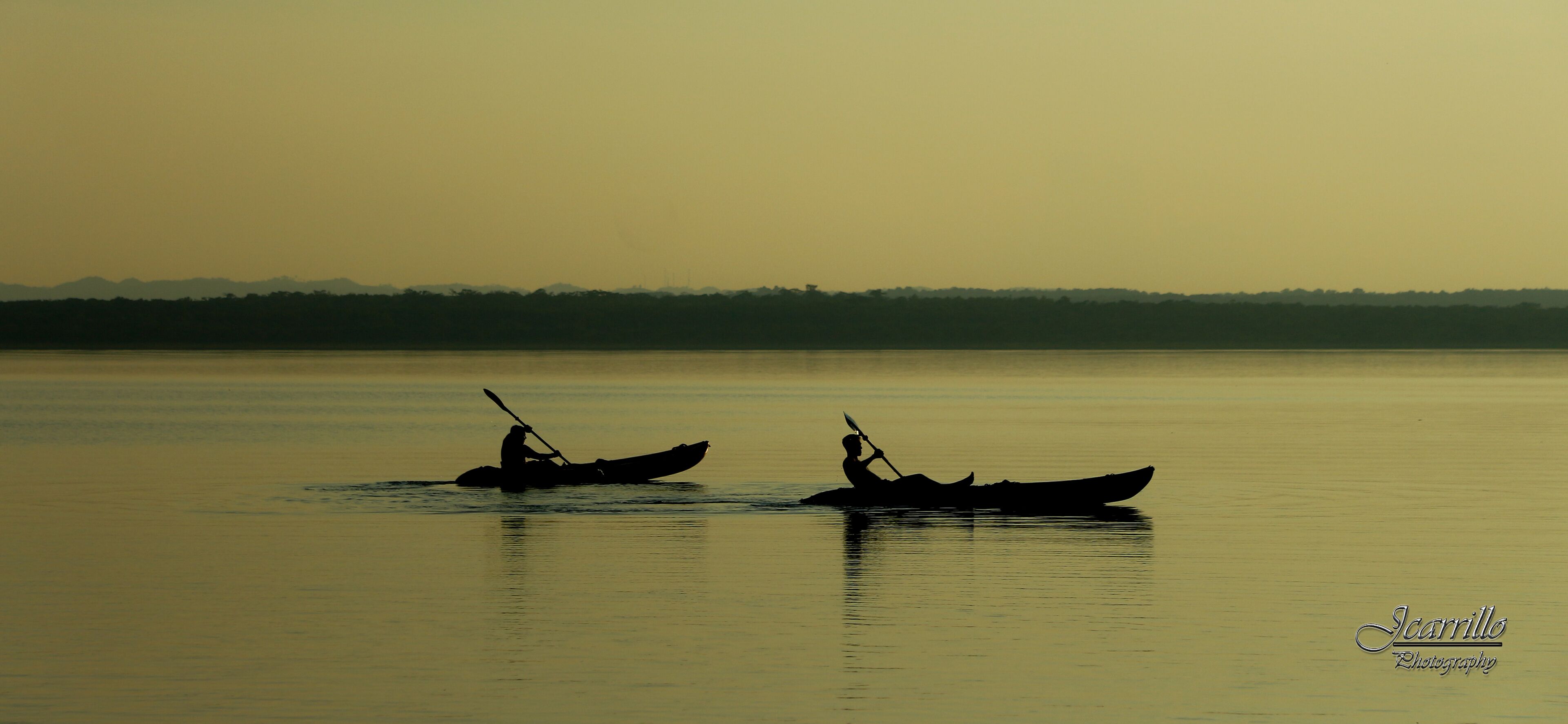 Two boats on calm water with a distant shoreline.