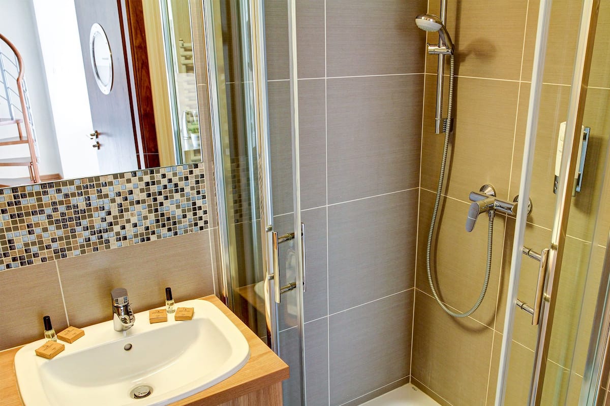 Ein modernes Badezimmer mit einer ein Glasfachwerk-Duschkabine, einem Holzwaschtisch mit Waschbecken und einer gefliesten Spritzschutzwand.