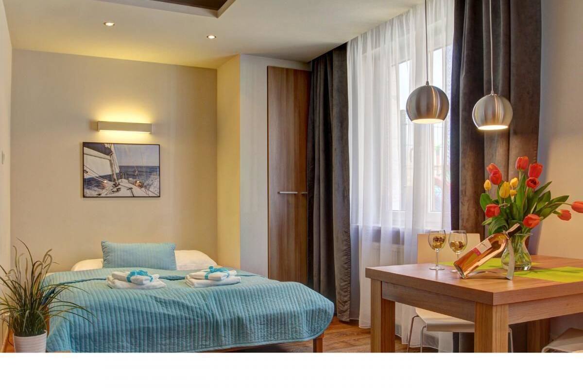 Ein Hotelzimmer mit einem Bett, einem Esstisch mit einer Vase voller Tulpen und einem Gemälde an der Wand.