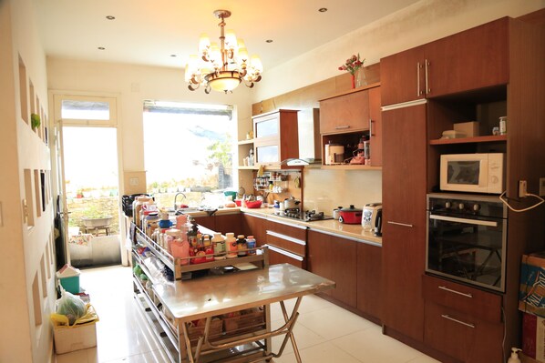 A kitchen with wooden cabinets, a stainless steel table, and a chandelier.