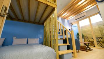 A bedroom with a bed, a wooden staircase, and a view of the outside.