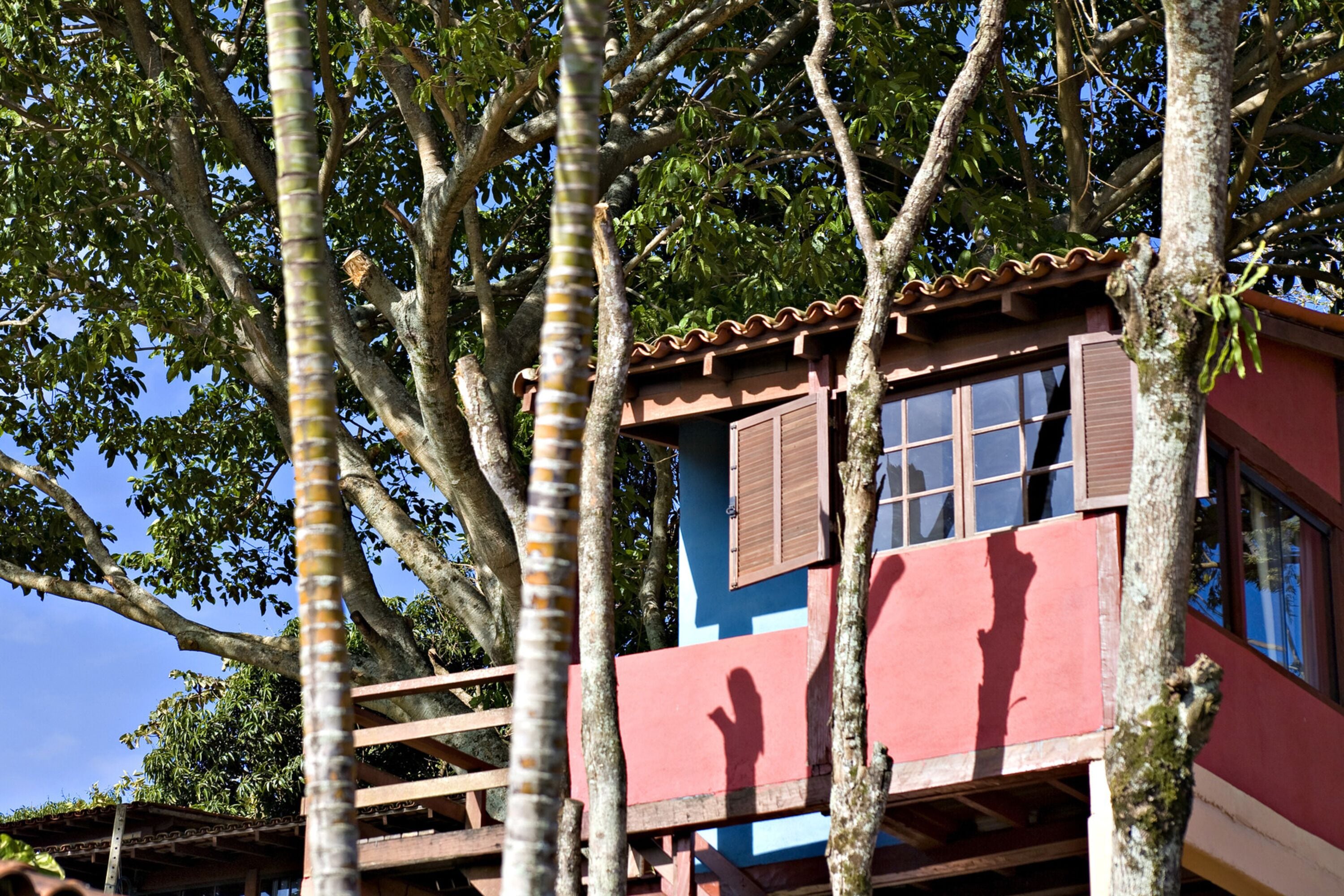 A colorful building with a balcony, surrounded by trees.