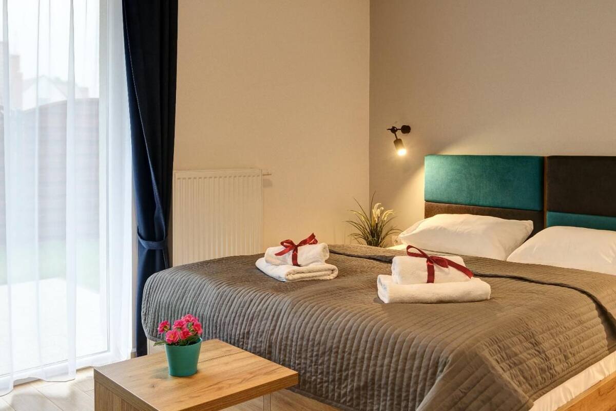Una cama bien hecha con toallas y una mesita con un florero.