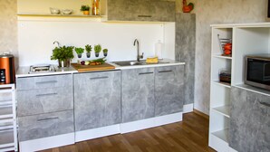 A modern kitchen with grey cabinets, a wooden countertop, and a built-in microwave. - Apartments Vogelsang - 3-room apartment (Kramerhof)