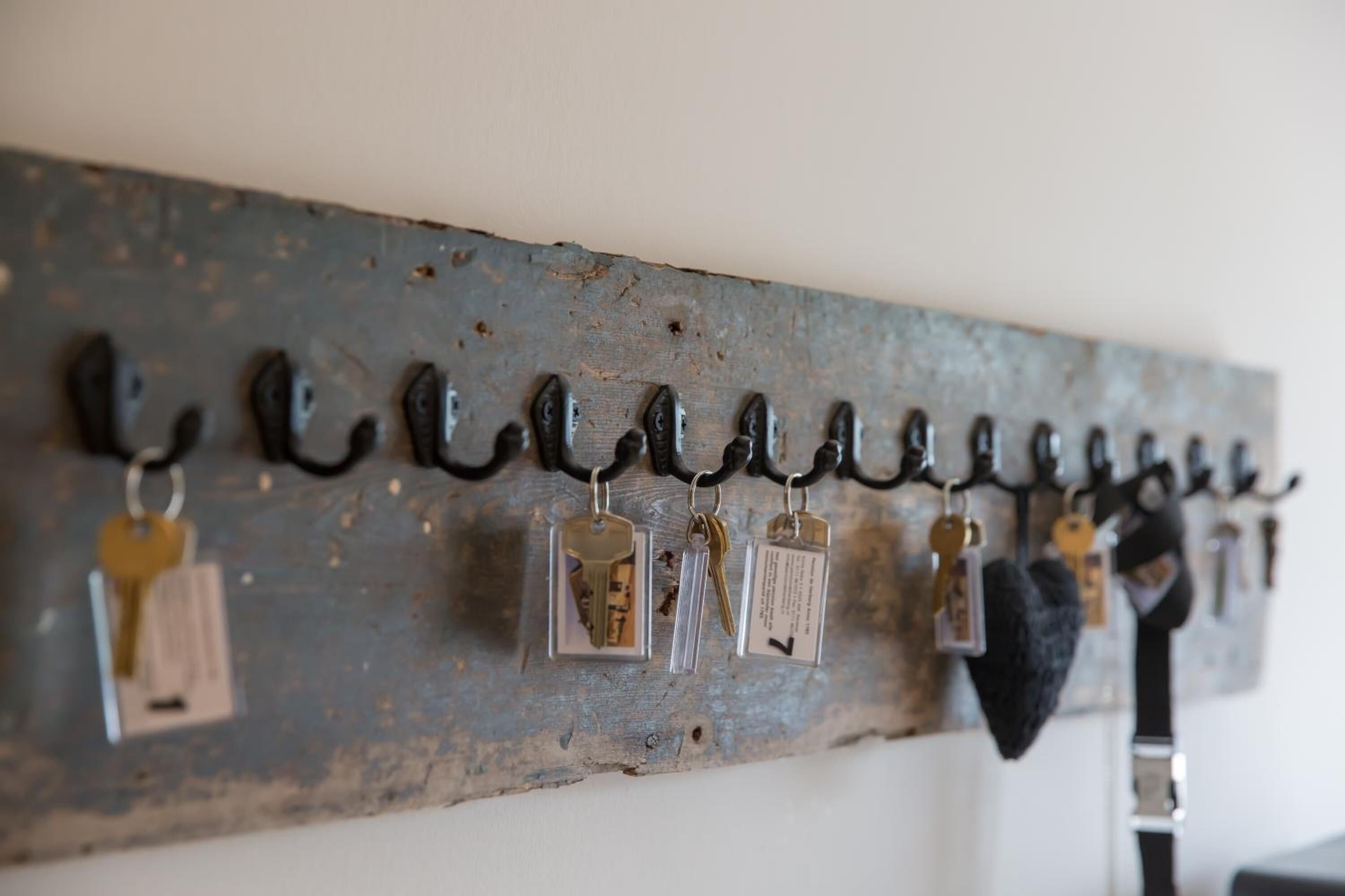 Un perchero metálico de pared con varias llaves y etiquetas para llaves.