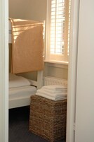 Una habitación pequeña y acogedora con literas, una ventana con persianas, un radiador y una cesta de mimbre.