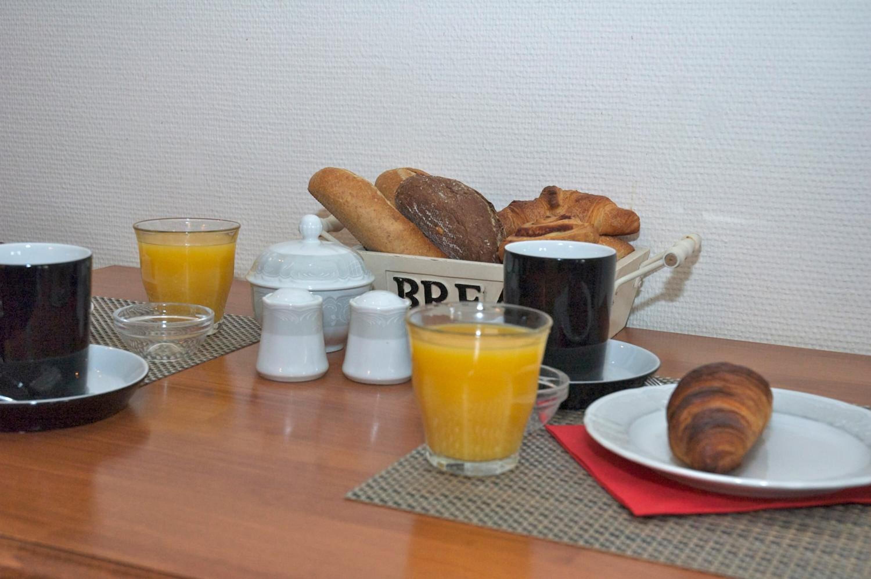 A breakfast table with croissants, bread, and orange juice.