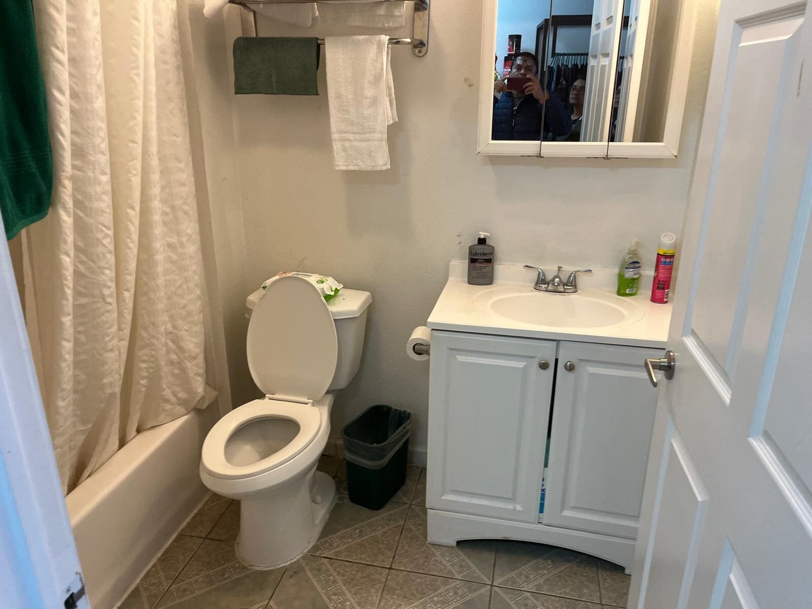 A bathroom with a toilet, sink, and mirror.