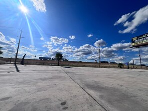 A wide, empty parking lot with a clear sky and a billboard advertising a law office.