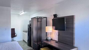 Hotellihuone, jossa on kaksi sänkyä, kirjoituspöytä lampun kanssa, televisio, minibaari ja pieni oleskelualue.