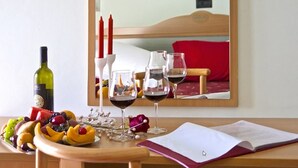 A neatly arranged table with a bottle of wine, glasses, a fruit platter, and a book. - Hotel Hamilton (Misano Adriatico)