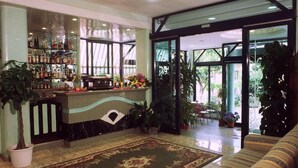 A lobby with a bar area, seating, and potted plants. - Hotel Hamilton (Misano Adriatico)