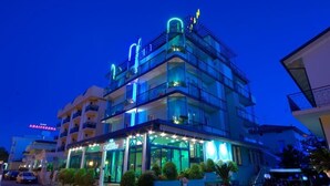 A multi-story hotel with balconies, a well-lit entrance, and a visible sign for a restaurant. - Hotel Hamilton (Misano Adriatico)