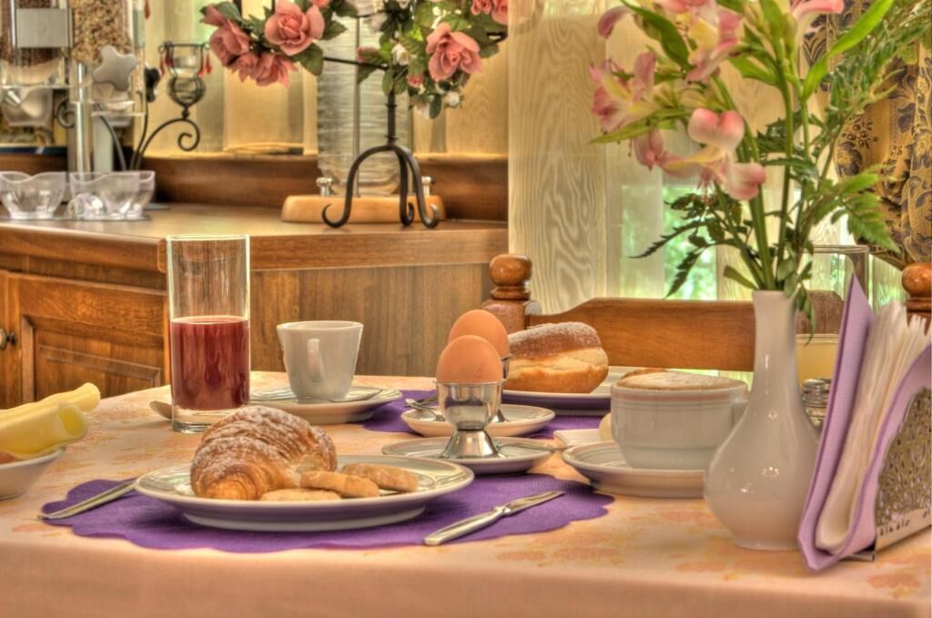 A breakfast setting with croissants, eggs, and a glass of juice on a table with a purple placemat.