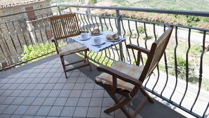 Un balcon avec une table dressée pour deux personnes, deux chaises et une vue imprenable sur la campagne.