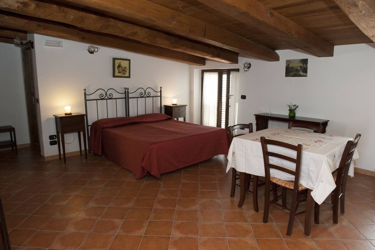 Ein Schlafzimmer mit einem Bett, Nachttischen, einem Tisch mit Stühlen und einem Fenster.