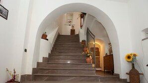 Un escalier avec un mur blanc et une porte en arc menant à une pièce.